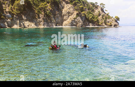 Scuba divers with oxygen tank preparing for diving entering in the beautiful Greece turquoise sea. Summer holiday activity. Stock Photo
