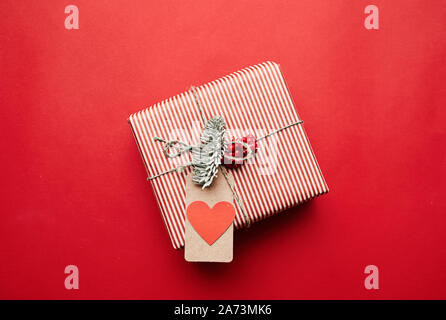 Image of gift box in wrapping paper with greeting card on it isolated on red background Stock Photo