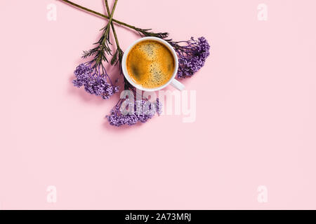 White cup of coffee and flowers on isolated pink desk. Flat lay, top view, copy space. Stock Photo