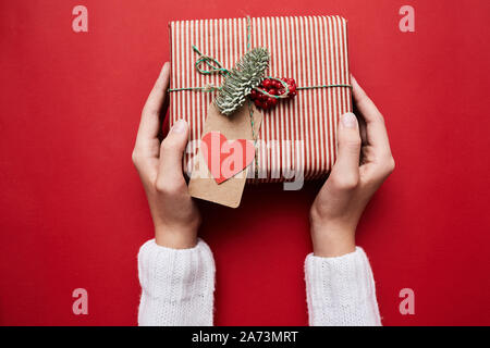 Close-up of woman holding gift box with greeting card for Valentine's Day isolated on red background Stock Photo