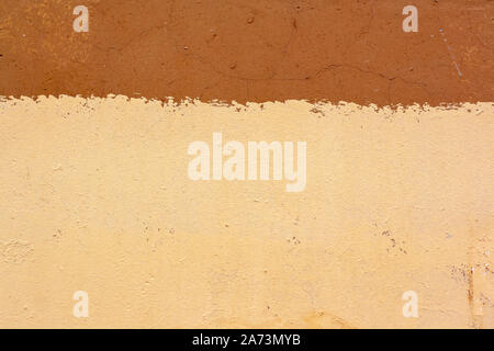 Texture of cracked old plastered wall divided into two colors yellow and brown. A lot of cracks and scratches. Copy space. Stock Photo