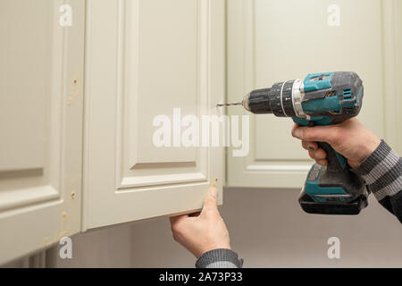 Man using electronic drill to install a cabinet Stock Photo