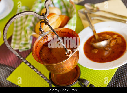 Hearty and spicy Bograc - Slovenian variety of Hungarian goulash cooked from three types of meat and potatoes traditionally served in copper cauldron Stock Photo