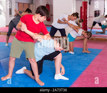 Mixed age group at self protection workout, training attack movements in pairs Stock Photo