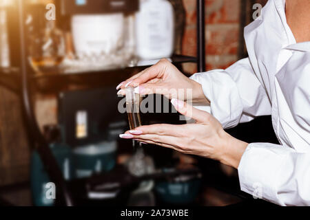 Closeup of a small bottle of perfume, oil, cosmetics on the hand of a beautiful woman. Beauty salon, cosmetology, Spa concepts Stock Photo