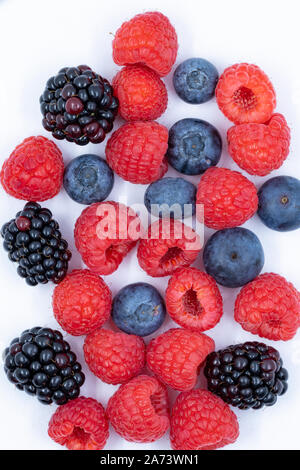 blueberries raspberries blackberries on a white background overhead macro shot Stock Photo