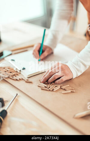 Female carpenter working with wooden dowels in carpentry woodwork workshop, selective focus Stock Photo