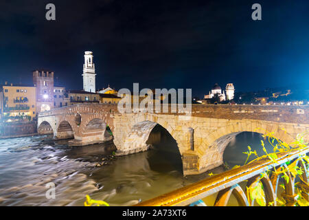 Scenic view of ancient Roman arch bridge Ponte Pietra crossing Adige River in Verona at night, Italy Stock Photo