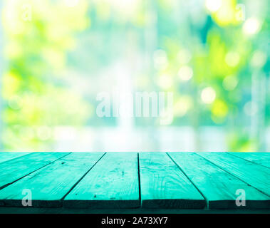 Green wood table top on blur abstract green garden from window view background. Stock Photo