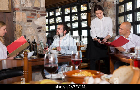 Guests of the country restaurant discuss menu with waitress Stock Photo