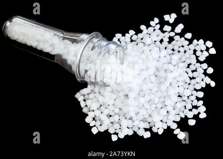 Polypropylene (PP) granules with blow injection molding bottle preform isolated on black background, selective focus. Stock Photo