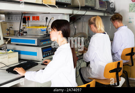 Multiracial group of students performing experiments on lab equipment in modern university research laboratory Stock Photo