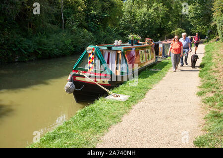 Many people walk along the towpath at Stoke Bruerne with narrowboats moored alongside Stock Photo