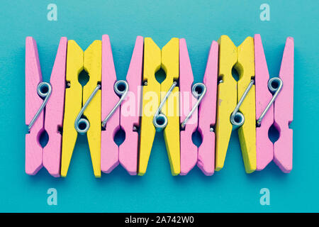 Bright colorful abstract background. Yellow and pink clothespins on a blue surface. Creative minimalist design. Stock Photo
