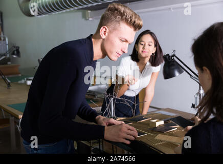 Model Guy Working Focused guy working on architectural model with student group in ...