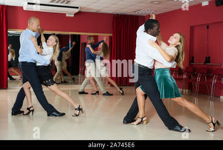 Young smiling people practicing passionate samba in dance class Stock Photo