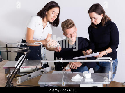 Group of architects working in design and engineering office, discussing elements of new architectural model Stock Photo