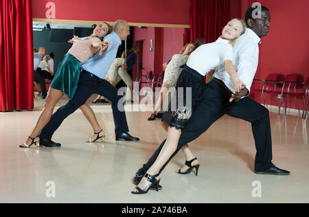 Young smiling people practicing passionate samba in dance class Stock Photo
