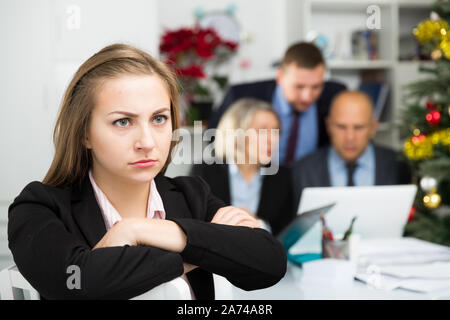 Business team tensely solving problems in office with upset woman foreground Stock Photo