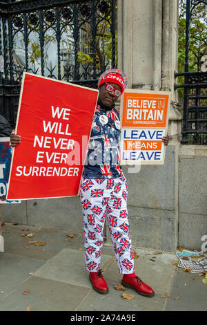 Westminster, London, UK. 29th October, 2019. Brexit leave campaigner Joseph Afrane holds We Will Never Ever Surrender and Believe in Britain Leave Means Leave signs outside the House of Commons on the day a General Election is called. Credit: Maureen McLean/Alamy Stock Photo