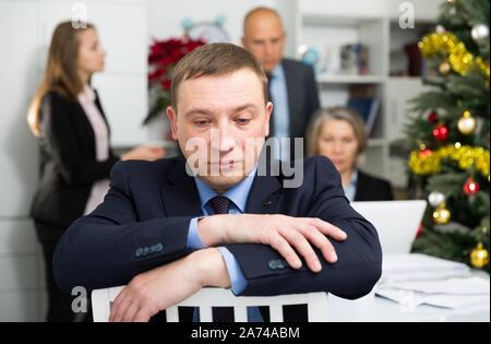 Business team tensely solving problems in office with offended man foreground Stock Photo