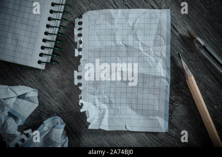 Crumpled empty pages and notebook lying on wooden surface Stock Photo
