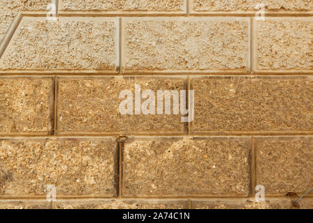 Stone brick wall made by non uniform textured concrete blocks with flat cuts. Stock Photo