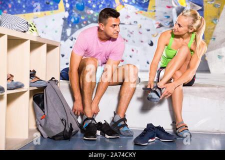 Smiling  pair of sports people dressing for mountaineering outfit for climbing on artificial rock wall indoors Stock Photo