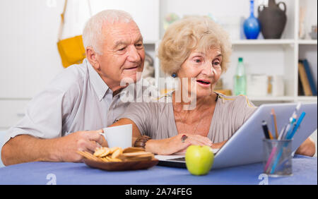 Portrait of cheerful mature spouses using laptop at home Stock Photo
