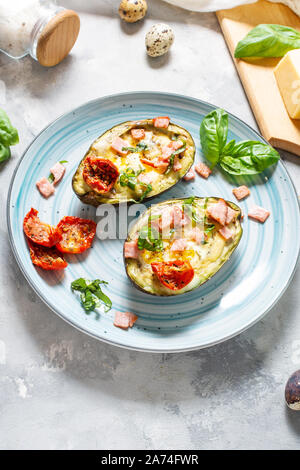 Keto diet - Avocado with ham, quail eggs, cheese on concrete background Stock Photo