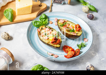 Keto diet - Avocado with ham, quail eggs, cheese on concrete background Stock Photo