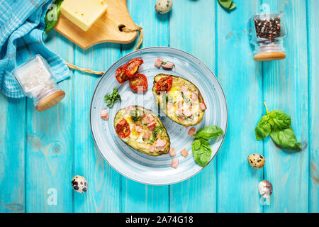 Keto diet: Avocado with ham, quail eggs, cheese on blue wood background. Top view Stock Photo