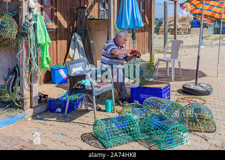 Local fisherman repairing fixing mending octopus nets traps pots trap pot net, Santa Luzia, East Algarve, Portugal. Stock Photo