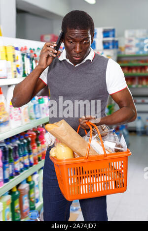 Nice African man talking by his mobile phone during shopping in store Stock Photo