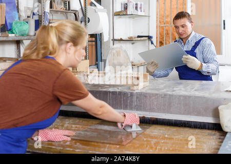 Active male worker with female apprentice working on glass washing machine in workshop Stock Photo