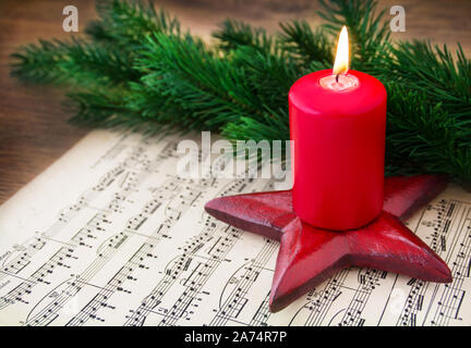 Christmas Music Sheet Music with Burning Candle Stock Photo