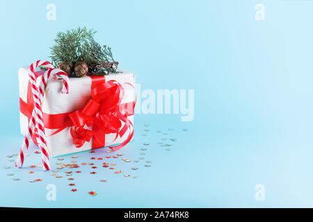 Christmas gift box with golden stars decorations and sparkles on pastel blue background. Minimal composition. New Year concept. Copy space, festive mi Stock Photo