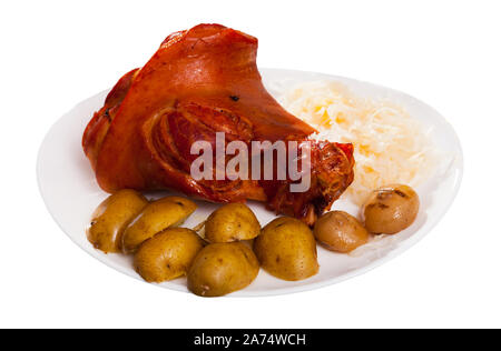 Appetizing pork knuckle and sauerkraut served with potatoes and onion. Isolated over white background Stock Photo
