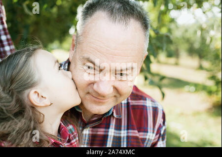 grandfather with granddaughter. Love you so much my grandpa. Girl kissing grandpa in thr park. Multi generation family enjoying in the park. Stock Photo