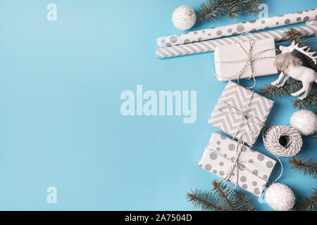 Christmas wrapping white gifts with decor branches on blue background. Flat lay. Top view. Copy space. Stock Photo
