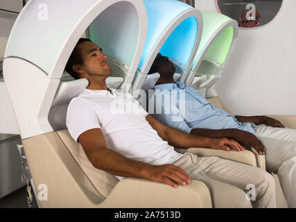 Relaxed male clients sitting in armchairs for washing hair at barber shop, waiting for hairdresse Stock Photo