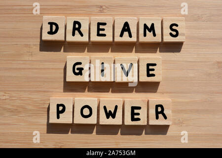 Dreams Give Power. Motivational words in 3d wooden alphabet letters on a bamboo wood background Stock Photo