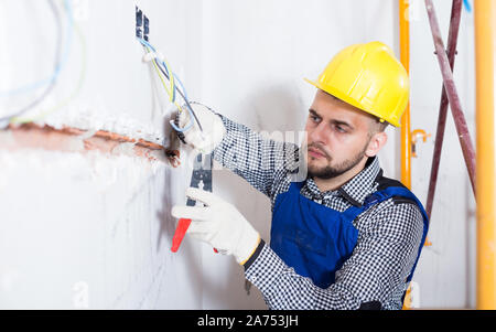 Workman is repairing the wiring at house. Stock Photo