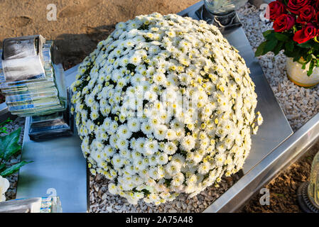 Chrysanthemums on a tombstone in the shape of a circle, in a Christian cemetery. Stock Photo