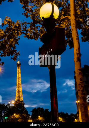 A iconic art deco metro sign across the river Seine with the Tour Eiffel in full lights after sunset Stock Photo