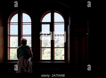 Woman looking through antic window Stock Photo