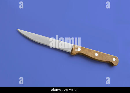 Kitchen accessories - medium utility knife with a wooden handle on a blue background. Cooking tools. Stock Photo