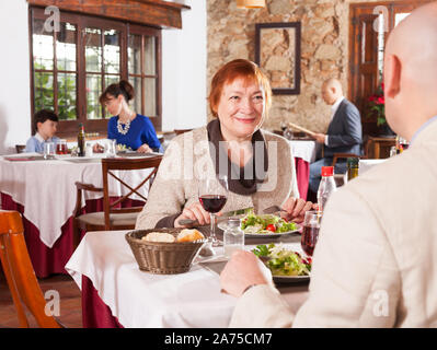 Portrait of happy senior woman and her adult son having dinner in restaurant Stock Photo