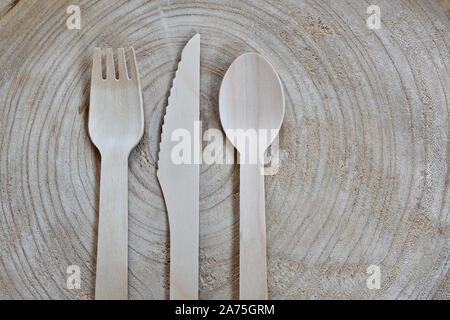 Plastic-free, disposable cutlery made of wood. Wooden fork, knife and spoon on a tree slice. Pro environmental concept, copy space for text and design Stock Photo