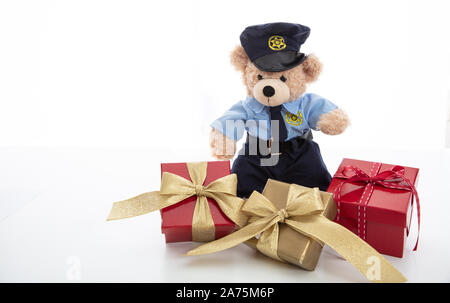 Police and christmas concept. Cute teddy bear in police officer uniform and xmas gift boxes isolated against white background Stock Photo